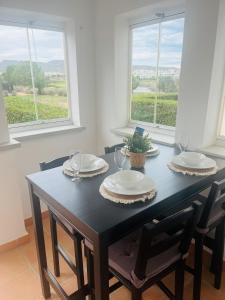 mesa de comedor negra con 2 sillas y 2 ventanas en La Casa Rosita, Hacienda Riquelme Golf Resort Sucina en Murcia