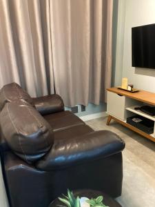 a living room with a leather chair and a television at Studio - Embaré - Santos, frente ao mar in Santos