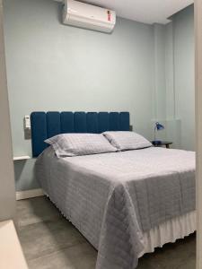 a bed with a blue headboard in a bedroom at Studio - Embaré - Santos, frente ao mar in Santos