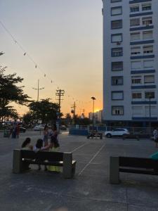 a group of people sitting on a bench in a parking lot at Studio - Embaré - Santos, frente ao mar in Santos