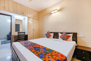 een slaapkamer met een groot bed en een kleurrijke deken bij FabHotel Valleyton Suites in Bangalore