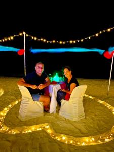 two people sitting in chairs on the beach at night at VIVA Beach Maldives in Hangnaameedhoo