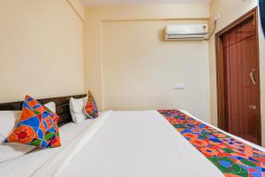 a bedroom with a white bed with colorful pillows at FabHotel Crystal Suites - Near Marathahalli Junction in Bengaluru