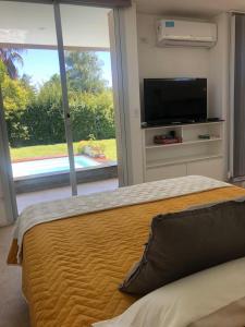 um quarto com uma cama grande e uma televisão de ecrã plano em Casa en Vistalba para dos personas con yacuzzi de temporada en la terraza em Luján de Cuyo