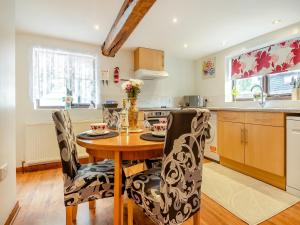 cocina con mesa de madera y sillas en Pear Tree Cottage en Banham