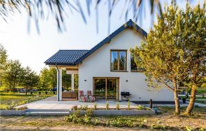 une maison blanche avec une terrasse et des arbres dans l'établissement Lovely Home In Nowa Wies Ostrdzka With Kitchen, 