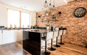 una cucina con muro di mattoni e un bar con sgabelli di Lovely Home In Nowa Wies Ostrdzka With Kitchen 