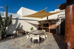 un patio con mesa, sillas y cactus en V PRINCESA vivienda con piscina climatizada y bbq, en Puerto del Carmen