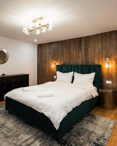 Schlafzimmer mit einem großen Bett mit einem grünen Kopfteil in der Unterkunft Rope Street eState Picturesque in Braşov