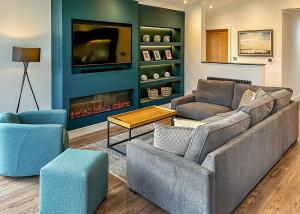 ein Wohnzimmer mit einem Sofa, Stühlen und einem TV in der Unterkunft Forest Hills Lodges in Coleford