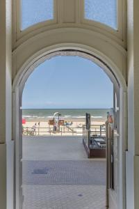 an archway leading to a beach with the ocean at Appartement 0401, VILLA COGELS MIDDELKERKE in Middelkerke