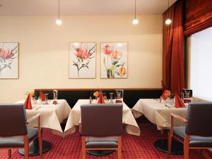 a dining room with two tables with white tablecloths at Morada Hotel Gothaer Hof in Gotha +5 photos
