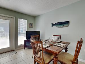 ein Esszimmer mit einem Tisch, Stühlen und einem TV in der Unterkunft Grand Caribbean #306 West in Perdido Key
