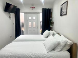 卢顿Great Studio near Airport - SUPER HOST 2 YEARS RUNNING!的一间卧室设有两张白色的床和窗户