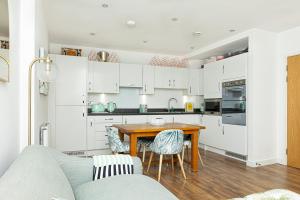 a kitchen with white cabinets and a wooden table at Stunning 1BR Flat in Hackney, 2 min London Fields in London