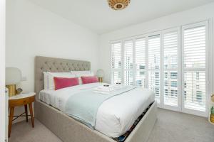a white bedroom with a large bed with pink pillows at Stunning 1BR Flat in Hackney, 2 min London Fields in London