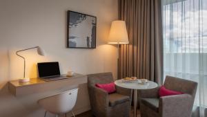 Habitación de hotel con escritorio y mesa con ordenador portátil. en The Gibson Hotel, en Dublín