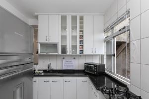 a kitchen with white cabinets and a black counter top at Apartamento 2 quartos no Buritis in Belo Horizonte