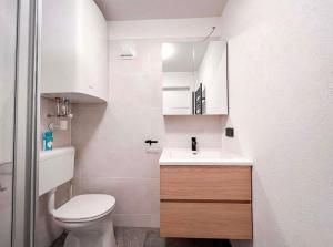 a white bathroom with a toilet and a sink at Das Hirscherl - Mountain Design Studio in Bad Kleinkirchheim