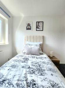 1 dormitorio con 1 cama con edredón blanco y negro en Tranquil Home Away from Home, en Newton Mearns