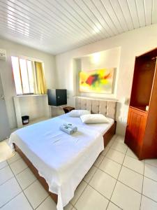 una camera da letto con un grande letto bianco e una televisione di Felicità Praia Hotel a Fortaleza