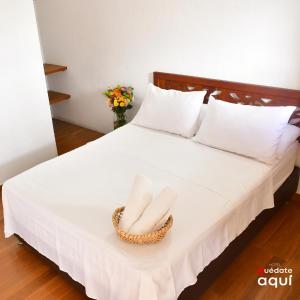 a white bed with two towels in a basket on it at Quedate Aqui Barichara - El Original in Barichara