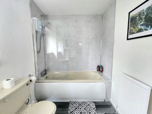 a white bathroom with a tub and a toilet at Tranquil Home Away from Home in Newton Mearns