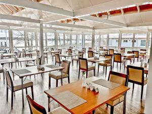 un comedor con mesas, sillas y ventanas en Morada Hotel Am Mellensee, en Klausdorf Brandenburg