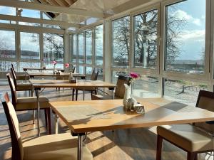 un restaurante con mesas y sillas de madera y ventanas en Morada Hotel Am Mellensee, en Klausdorf Brandenburg