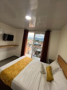 ein Hotelzimmer mit einem Bett und einem großen Fenster in der Unterkunft Hotel Olam Confort in Villavicencio