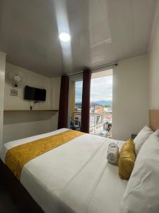 una camera d'albergo con un grande letto e una finestra di Hotel Olam Confort a Villavicencio