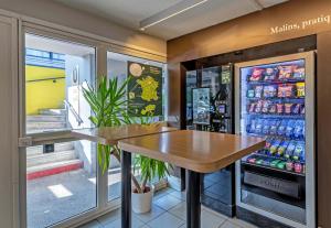 ein Restaurant mit einem Tisch vor einem Kühlschrank in der Unterkunft B&B HOTEL Morlaix in Saint-Martin-des-Champs