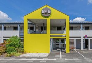 ein gelbes Gebäude mit einem bbq-Schild darauf in der Unterkunft B&B HOTEL Morlaix in Saint-Martin-des-Champs