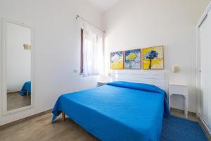 a bedroom with a blue bed and a mirror at Villa Bouganville Cala Sinzias in Castiadas