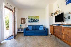 a living room with a blue couch and a tv at Villa Bouganville Cala Sinzias in Castiadas