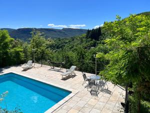 una piscina con sillas y una mesa con vistas a las montañas en La Roseraie - Gite avec piscine en Cévennes, en Roquedur