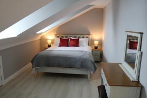 a bedroom with a bed with red pillows and a mirror at Church Suites Enniskillen in Enniskillen
