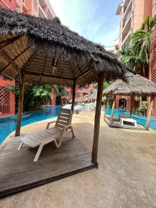 a chair under a straw umbrella next to a pool at Seven Seas Condo Pattaya - 7 seas pool view in Jomtien Beach