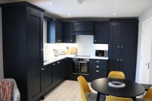 a kitchen with navy blue cabinets and a table and chairs at Church Suites Enniskillen in Enniskillen
