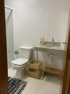 a white bathroom with a toilet and a sink at Casa Prado Bahia in Prado