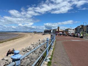 a beach with a blue fence and people on the beach at Shore Enough - Morecambe Sea Front Apartment in Heysham