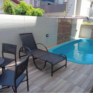 patio z 2 krzesłami i basenem w obiekcie Brisa Praiana lll w mieście Cabedelo