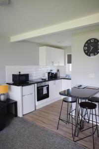 a kitchen with a table and a clock on the wall at Modern Airy Chalets short walk to beach, Nr Norfolk Broads & Great Yarmouth in Scratby