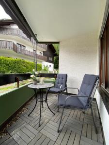 een patio met 2 stoelen en een tafel op een balkon bij Schwarzwaldidyll in Todtmoos