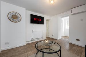 a living room with a table and a clock on the wall at The New Lodge - Cottage - Tv in every bedroom! in Pontardawe