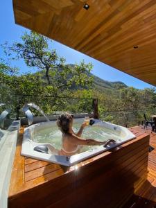 Eine Frau in einer Whirlpool-Badewanne auf dem Deck in der Unterkunft Casa Vértize, uma casa de alto padrão com Spa Hidro e vista espetacular in Cavalcante