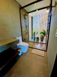 a bathroom with a toilet and a window at Casa Vértize, uma casa de alto padrão com Spa Hidro e vista espetacular in Cavalcante