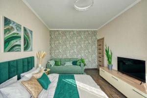 1 dormitorio con 1 cama y TV de pantalla plana en Green Boutique - квартира в изумрудных оттенках на Мынбаева, en Almaty