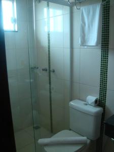 a bathroom with a toilet and a glass shower at HOTEL TOPAZIO in Cristalina