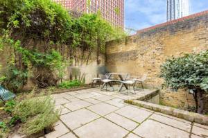 a patio with a table and chairs next to a brick wall at Shared Guest House 5 mins walk from Vauxhall and Nine Elms Station with off-site parking near US embassy in London